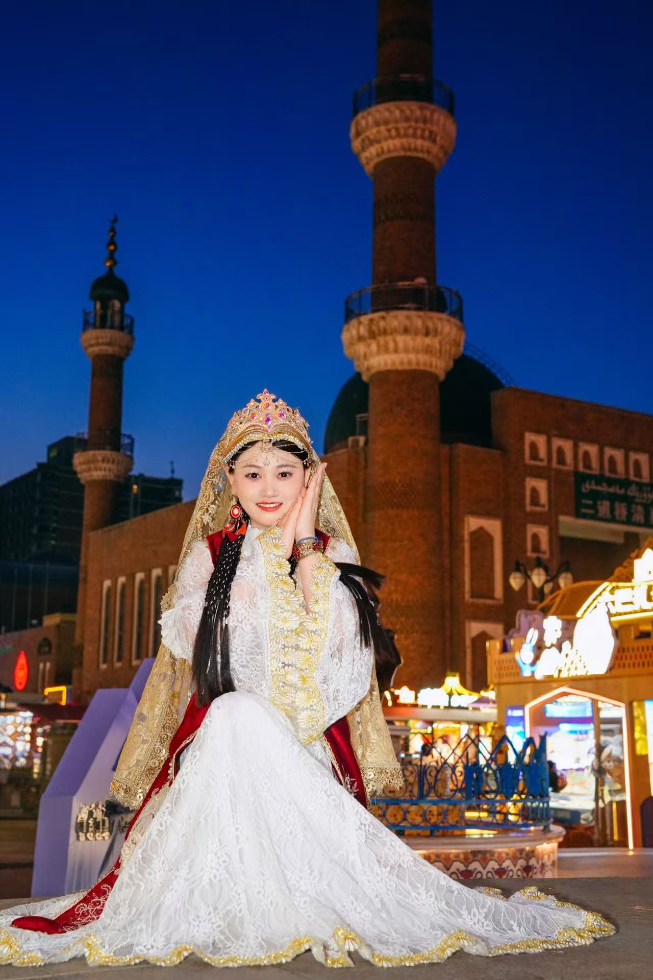 兰秀芹 Cassie Lan 个人照片，穿着民族服饰站在夜色建筑前